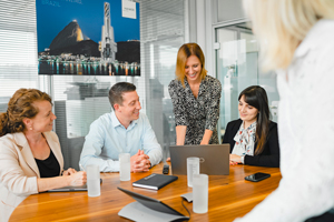 Plusieurs personnes sont assises autour d'une table ronde et regardent un ordinateur portable